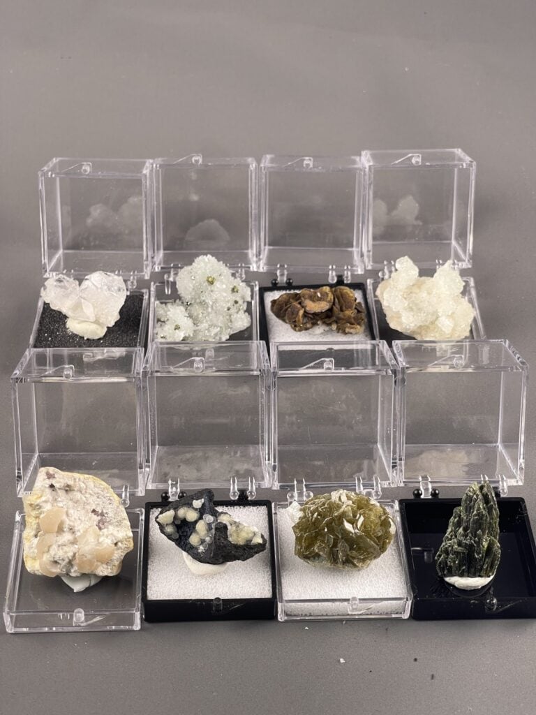 Boxed mineral specimens used for identification and study, showing different colors, lusters, and crystal forms