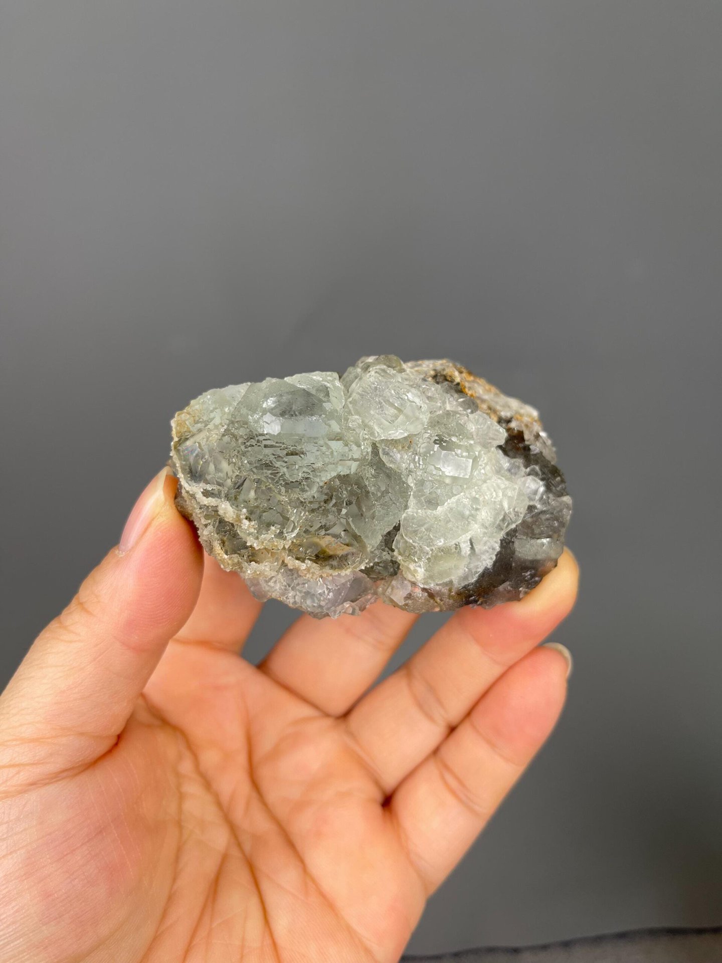 Front view of transparent green fluorite cube on matrix