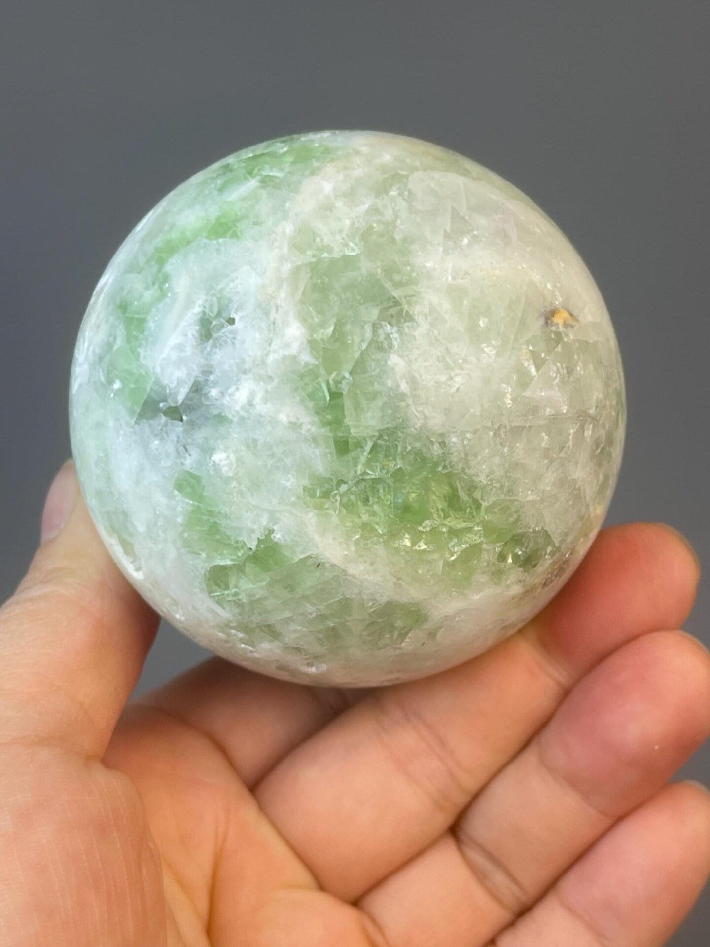 Carved fluorite sphere with natural green mineral patterning