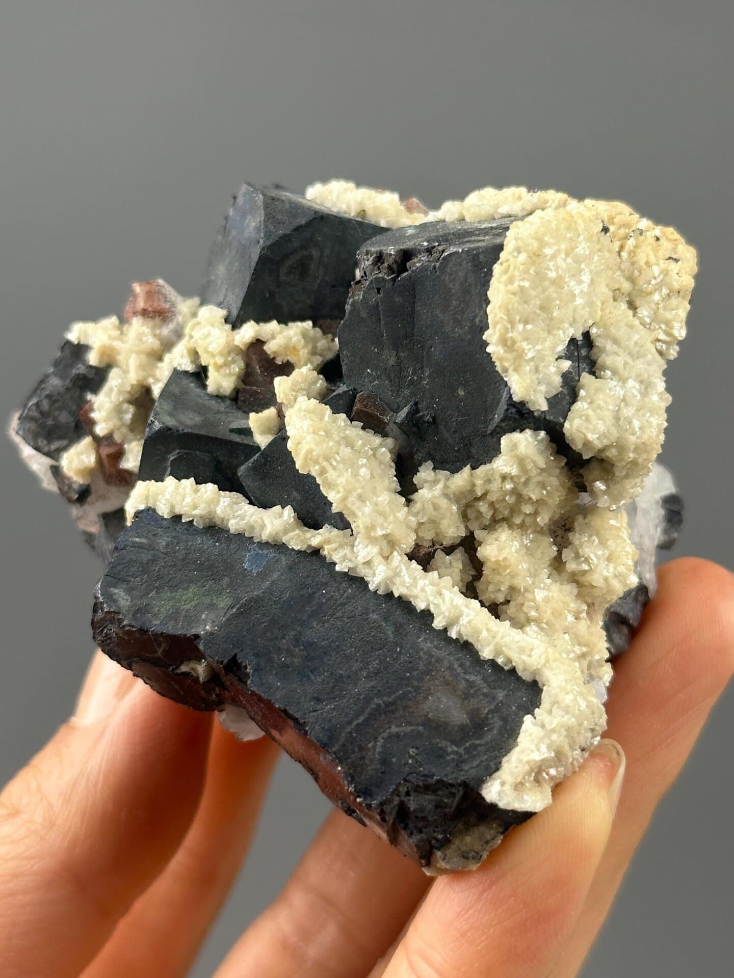 Front view of black iron ore cluster with calcite accents