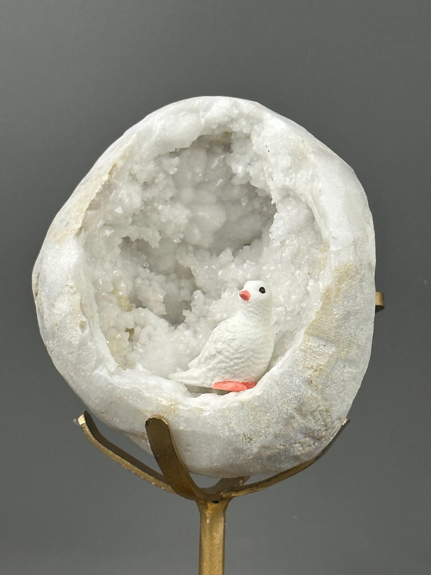 Side view of large quartz geode on gold stand