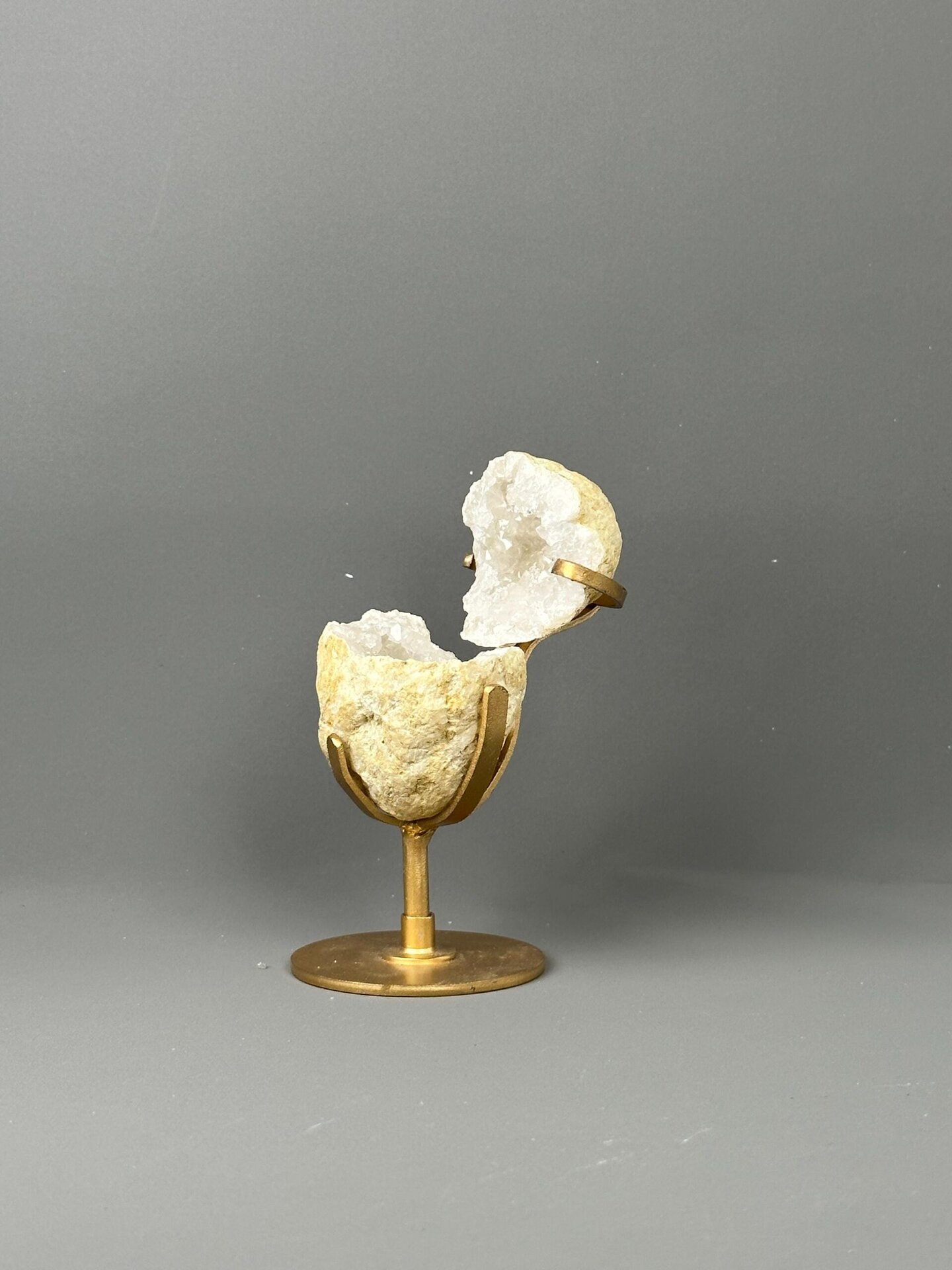 Side view of quartz geode on gold display base