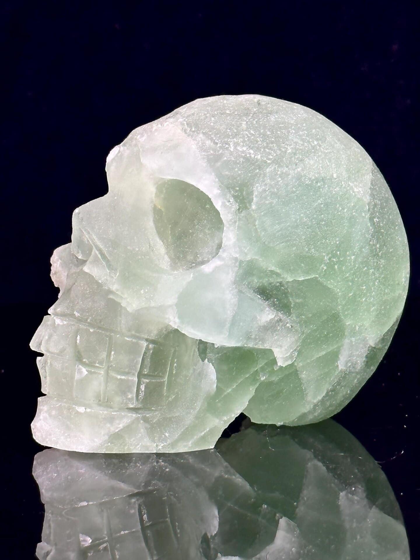 Hand-carved green fluorite geode skull with raw crystal interior