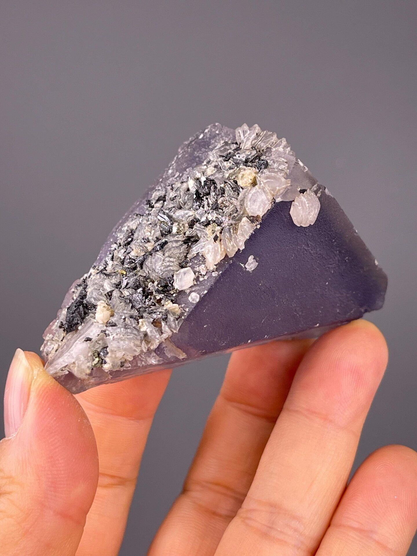 White calcite minerals encrusting purple fluorite crystal