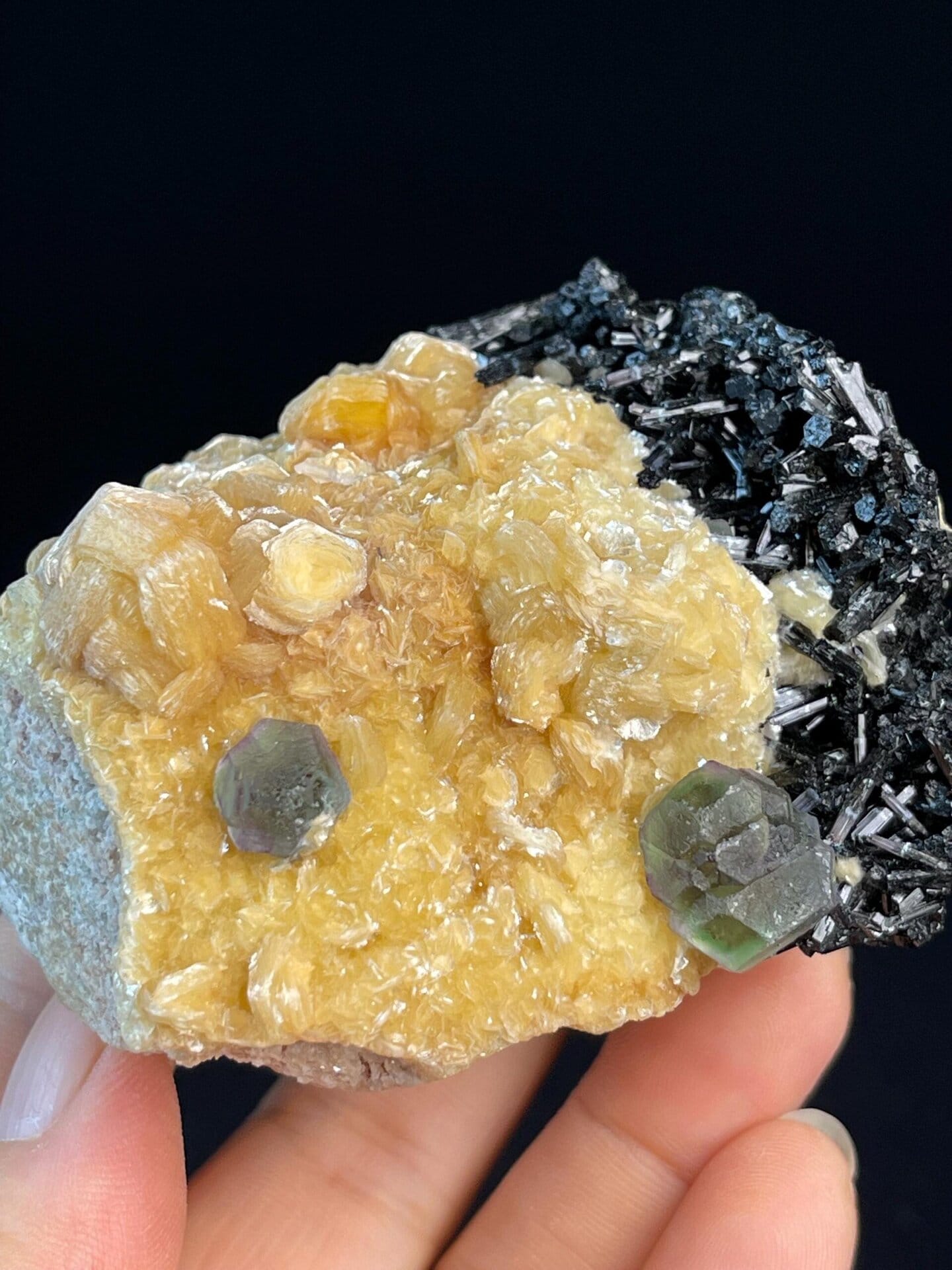 Green and purple fluorite beside black tourmaline on calcite