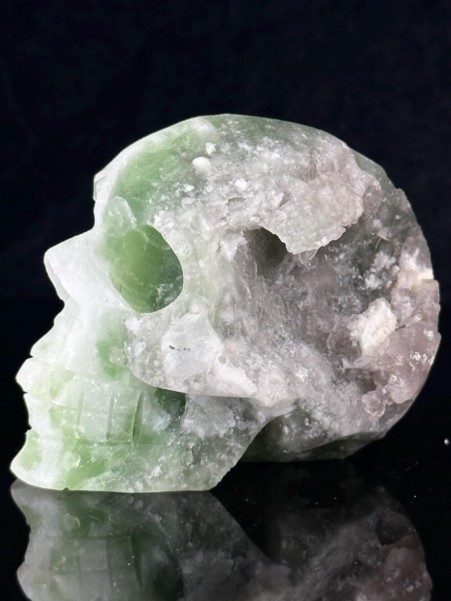 Hand-carved green fluorite skull with raw geode interior from China