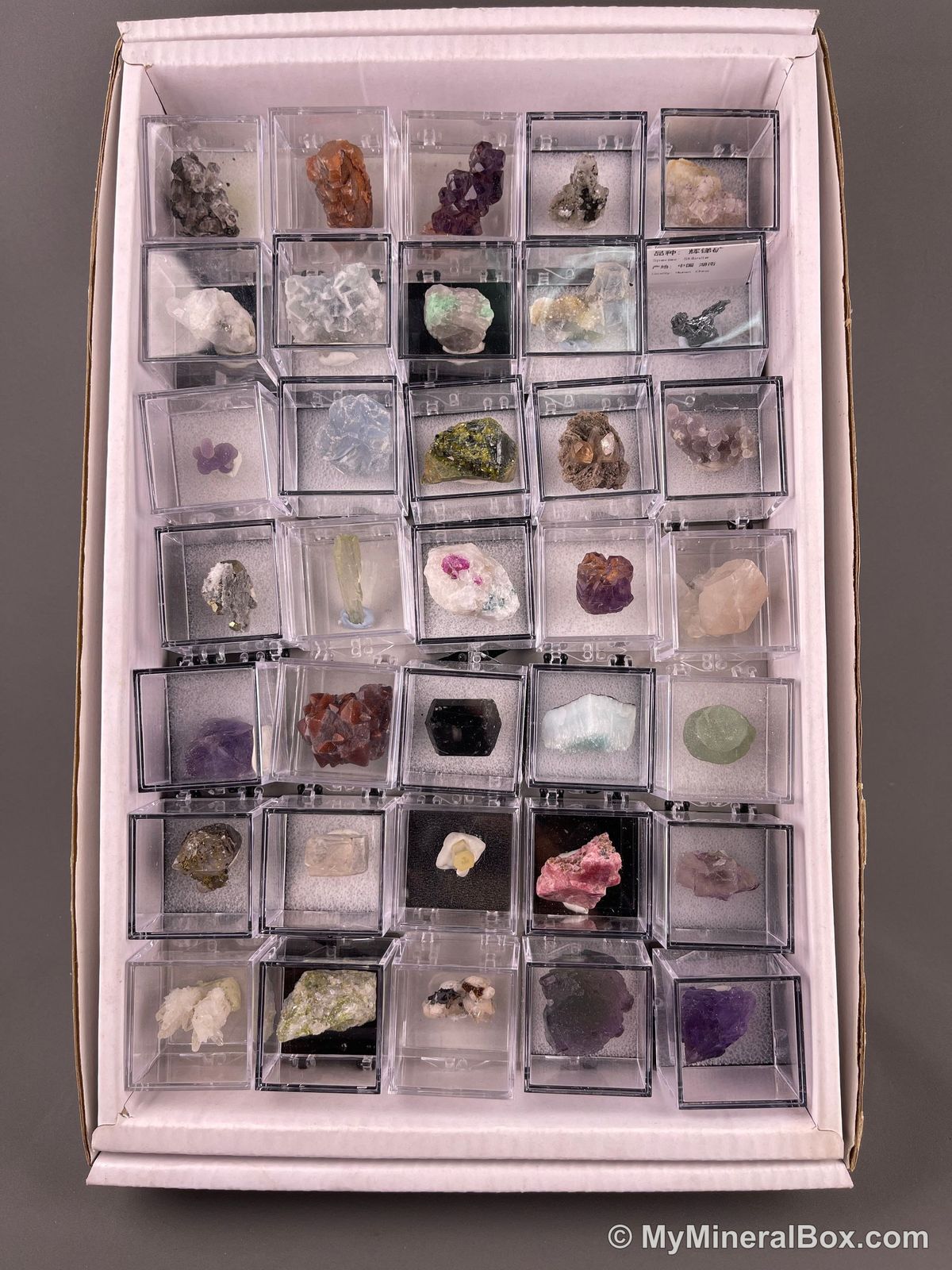 Bulk004 actual mixed mineral specimen box with about 35 different mini natural specimens, including likely fluorite, black tourmaline, quartz, stibnite, grape agate and green prehnite-type material.