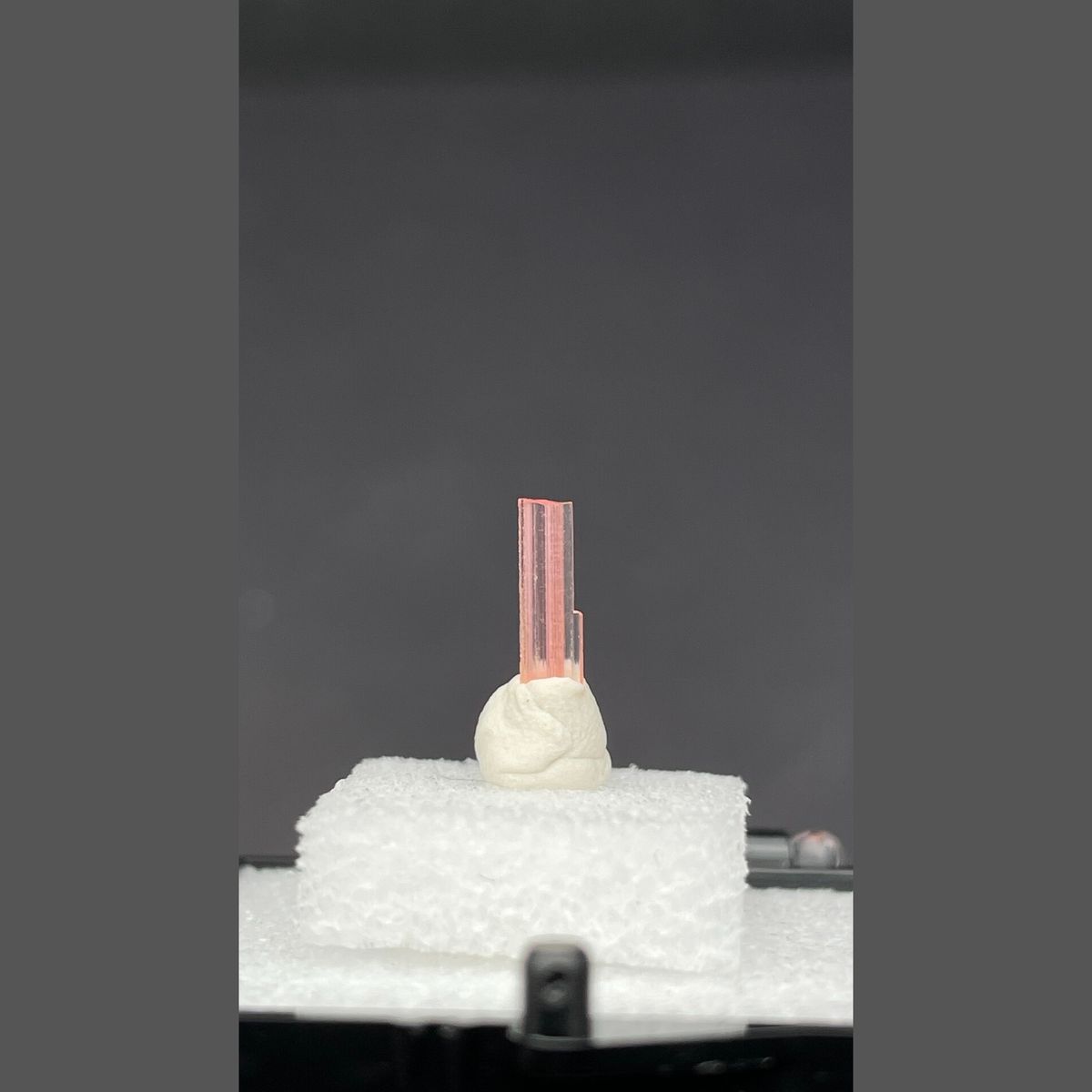 Tiny pale pink väyrynenite crystal on a display stand from Pakistan — complete view