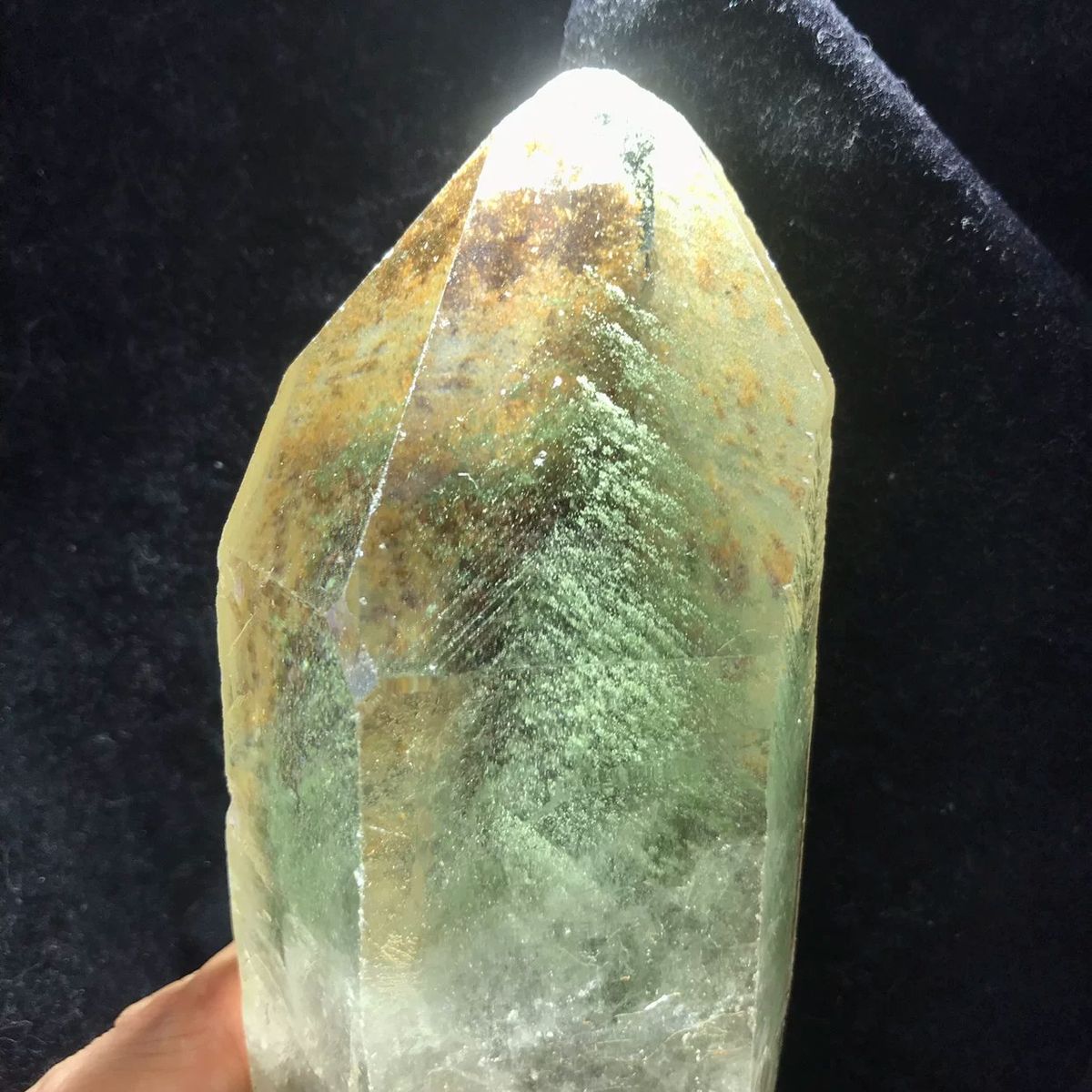 Backlit green phantom quartz point with layered green and rust phantoms