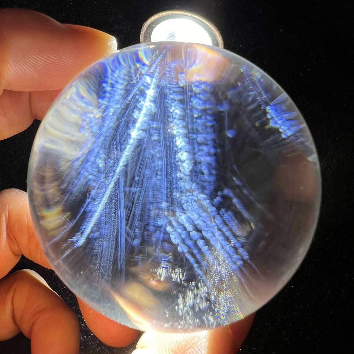 Torch-lit clear sphere crowded with deep blue fern-like needle sprays