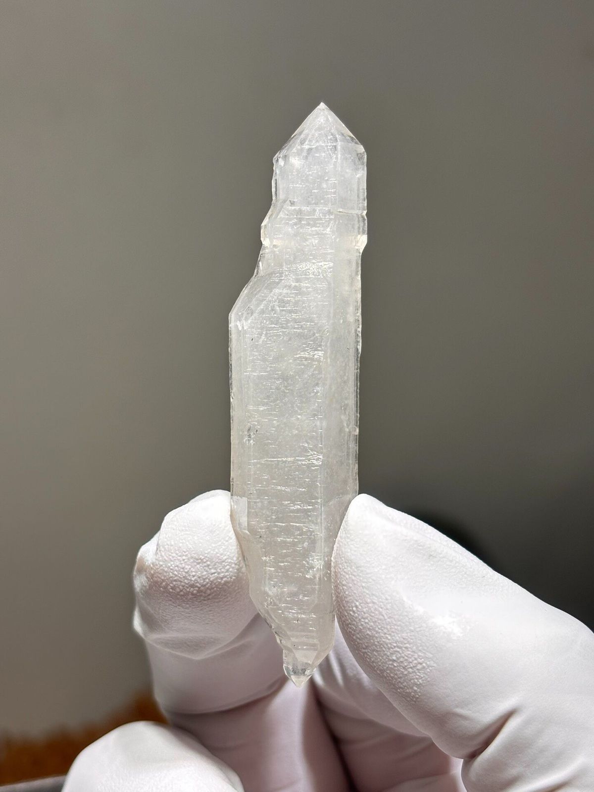 White sugar-core double-terminated quartz from Yunnan, China, held in gloved hand