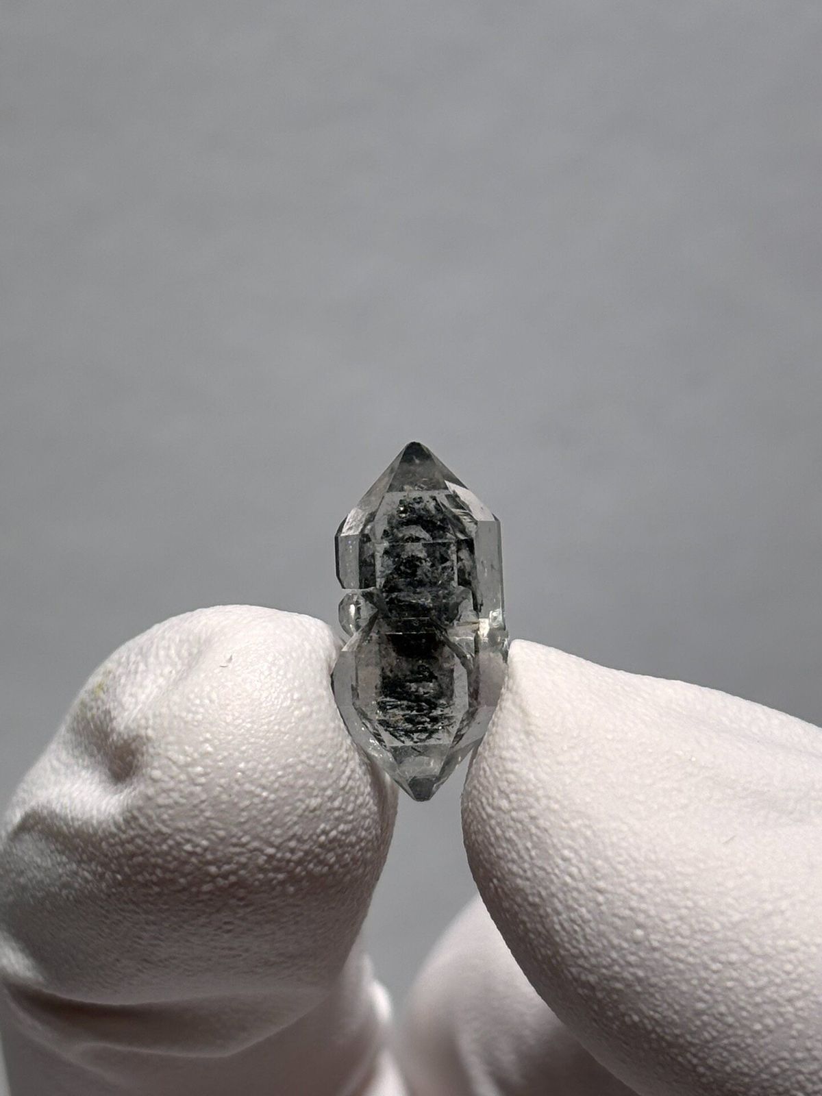 Very tiny black sugar-core double-terminated quartz from Yunnan, China, held in gloved hand