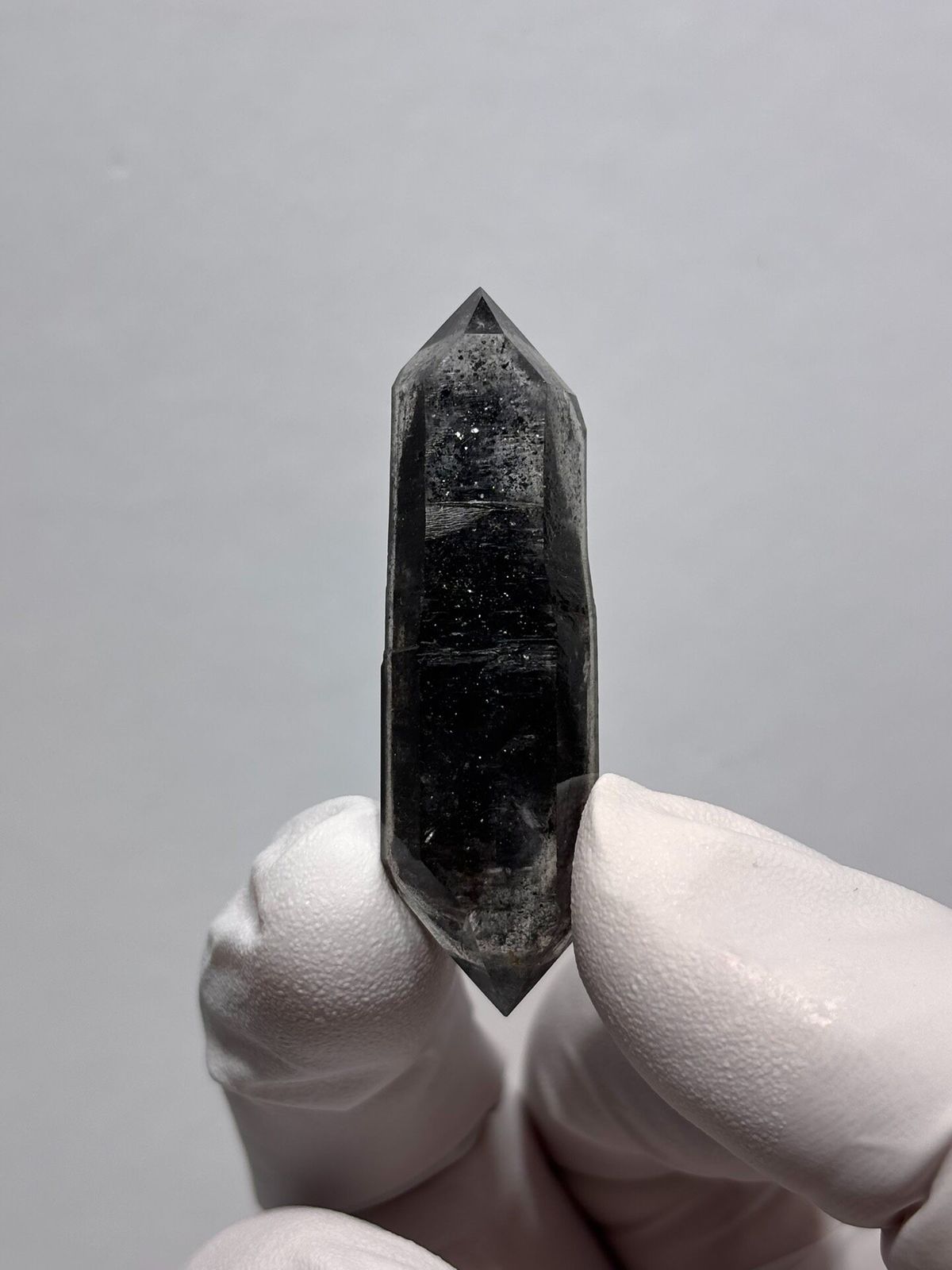 Black sugar-core double-terminated quartz from Yunnan, China, held in gloved hand