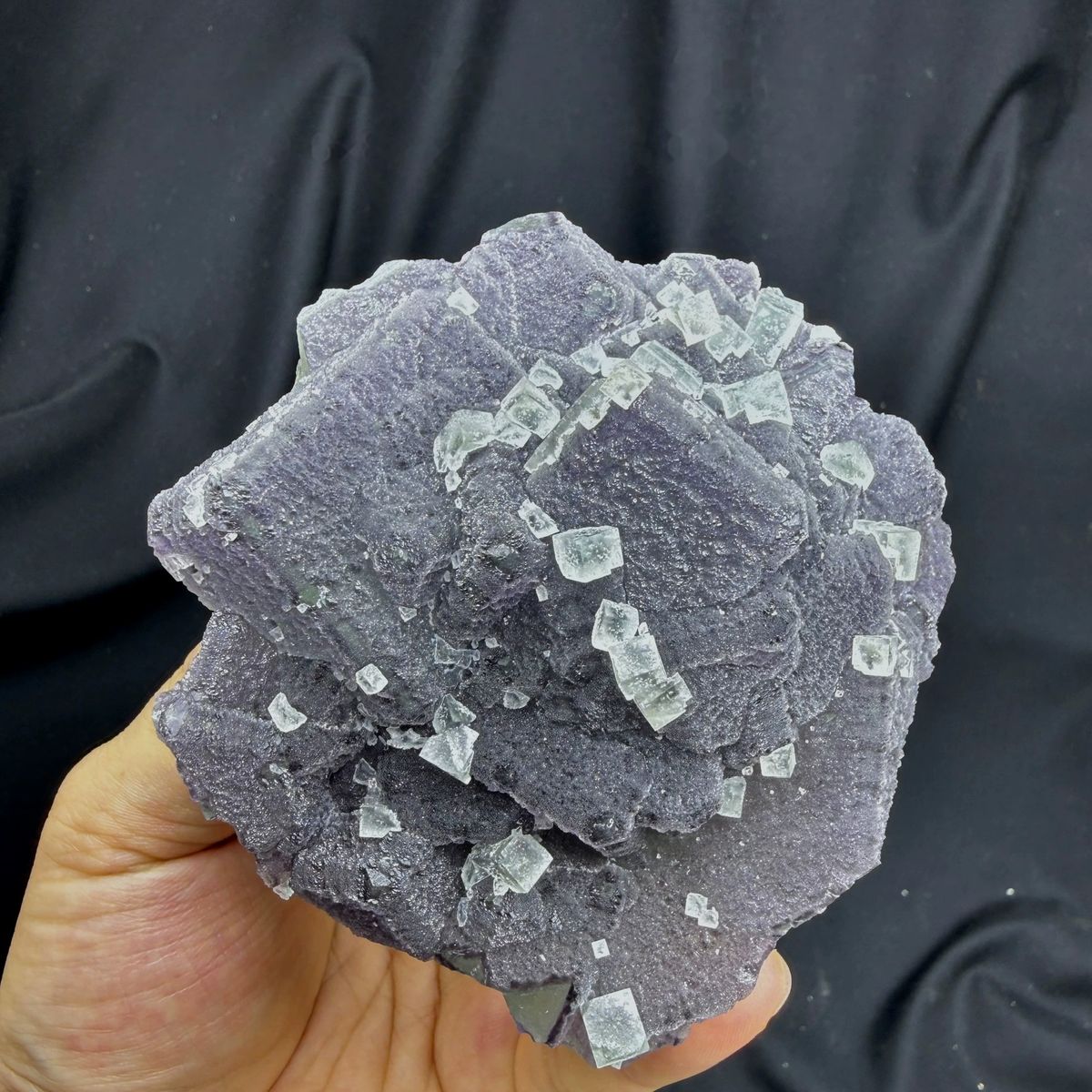 Muted lavender recrystallised fluorite with small green cubes from Fujian, China, held in hand