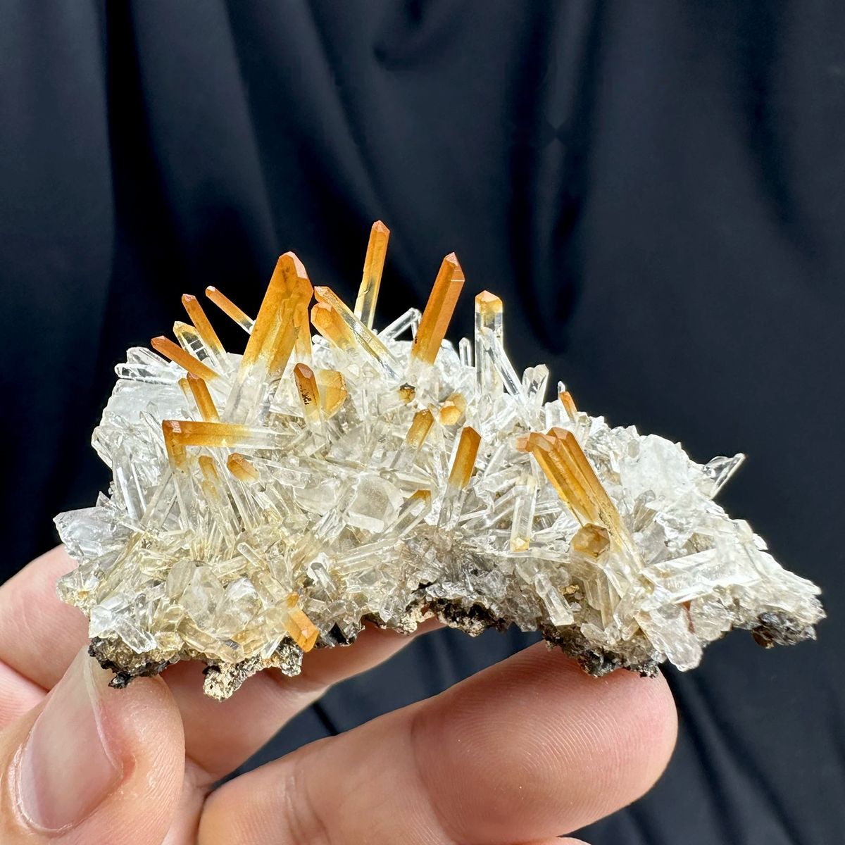 Orange-tipped clear quartz needle fan from Jinkouhe, Sichuan, China, held in hand