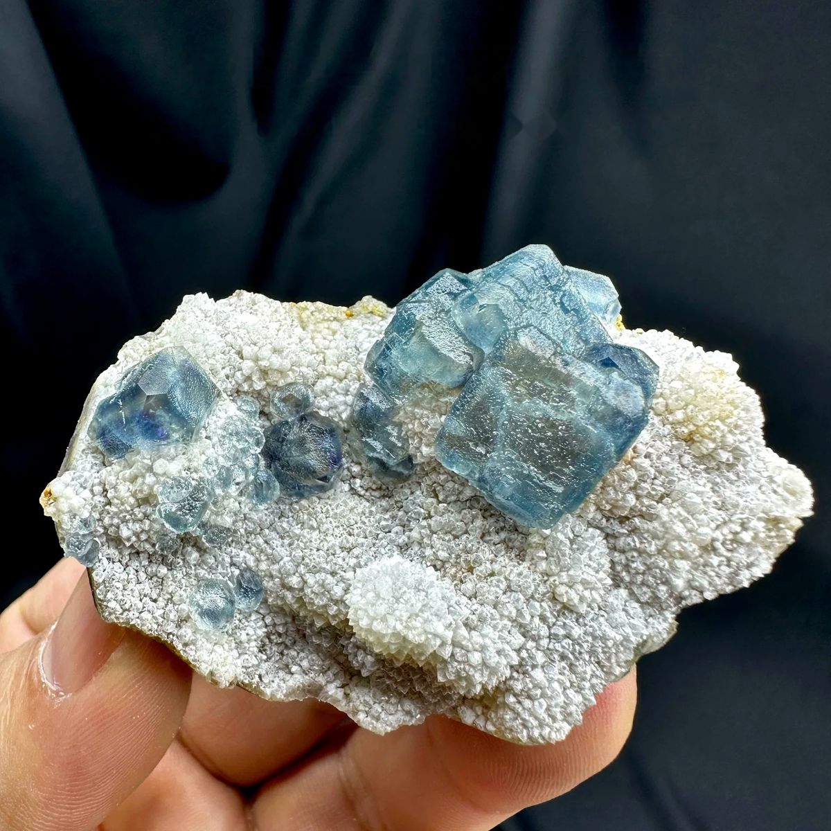Muted teal-blue fluorite cubes on white sugar-quartz from Fujian, China, held in hand