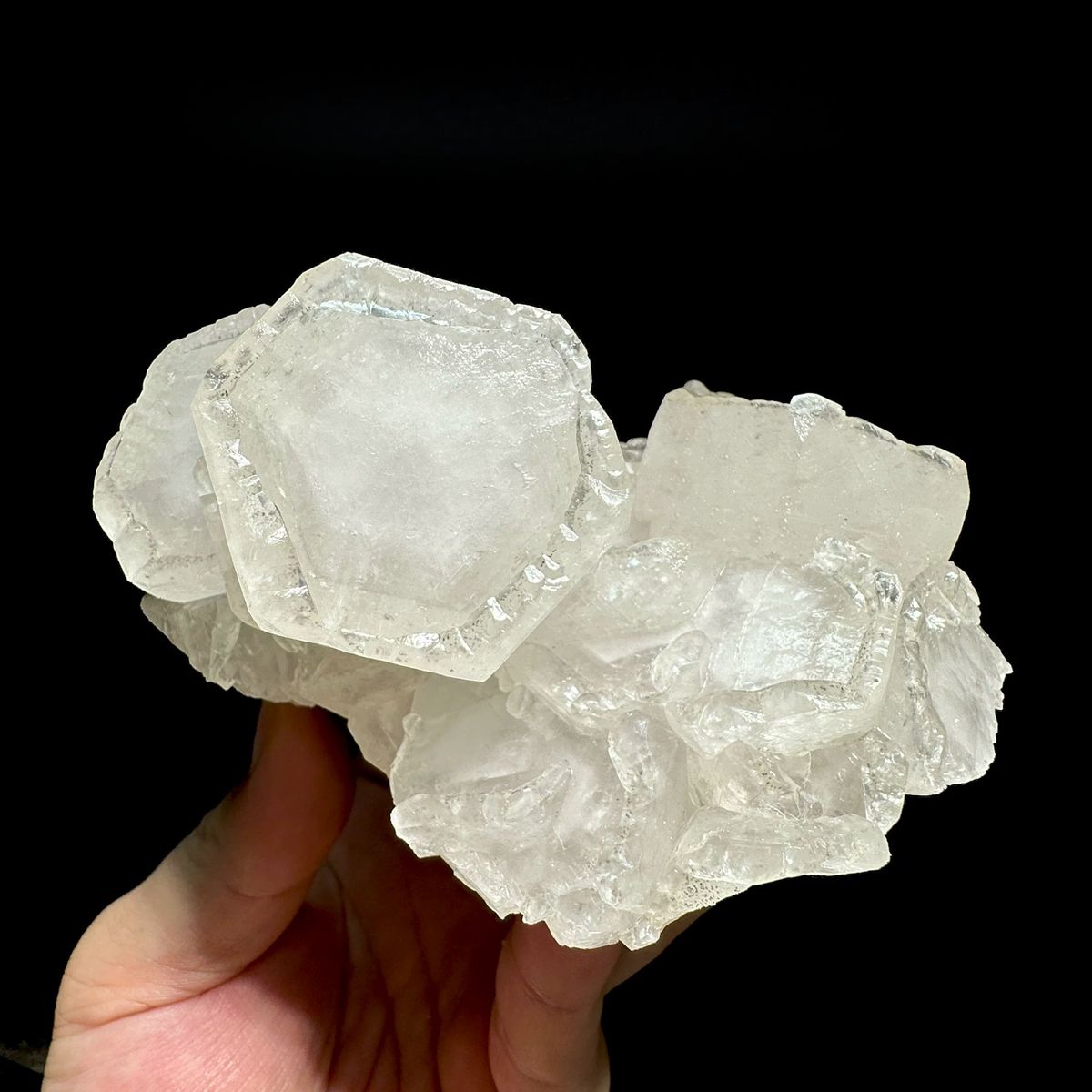 Group of large white hexagonal calcite crystals from Hunan, China, held in hand