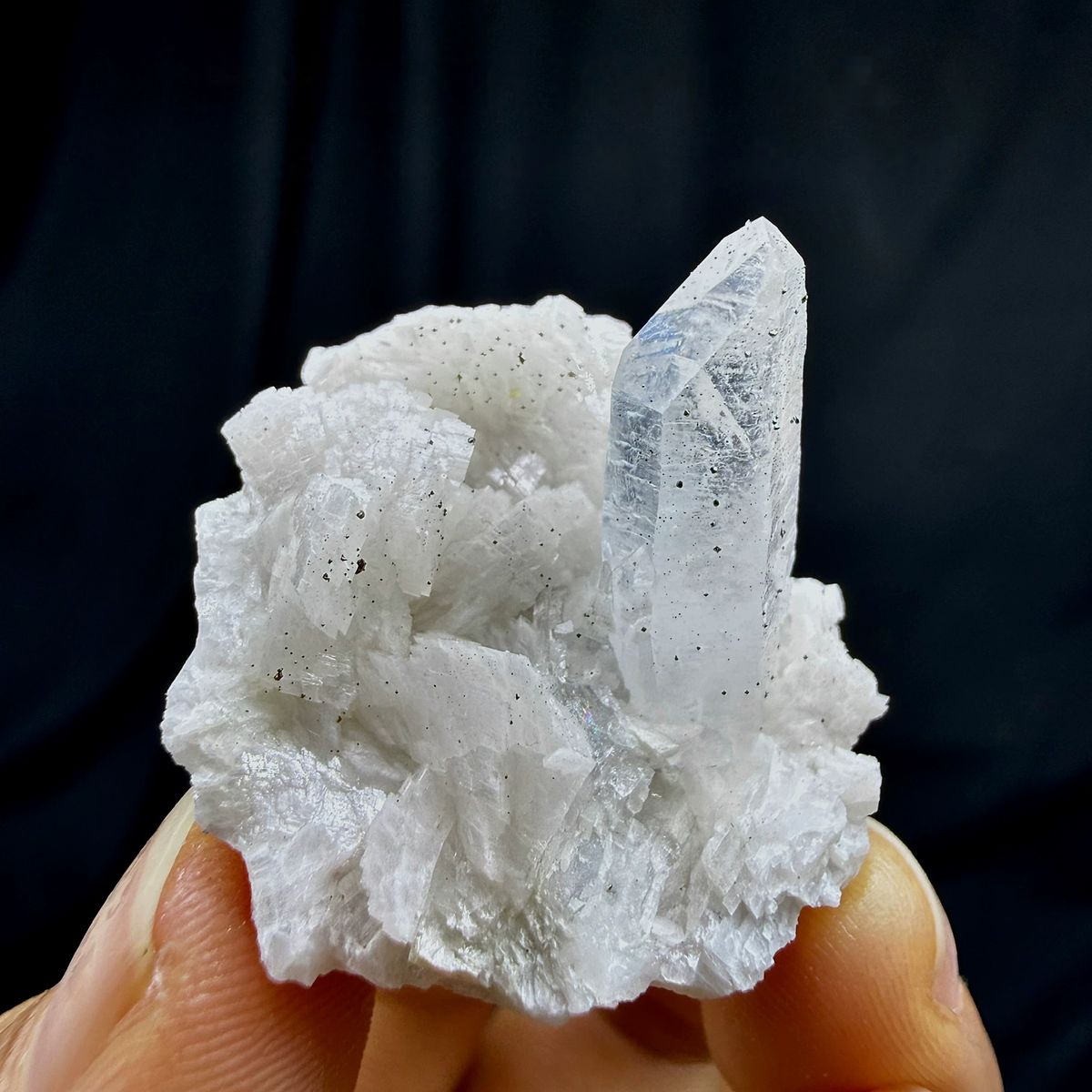 Clear quartz point on cream dolomite with pyrite from Guizhou, China, held in hand