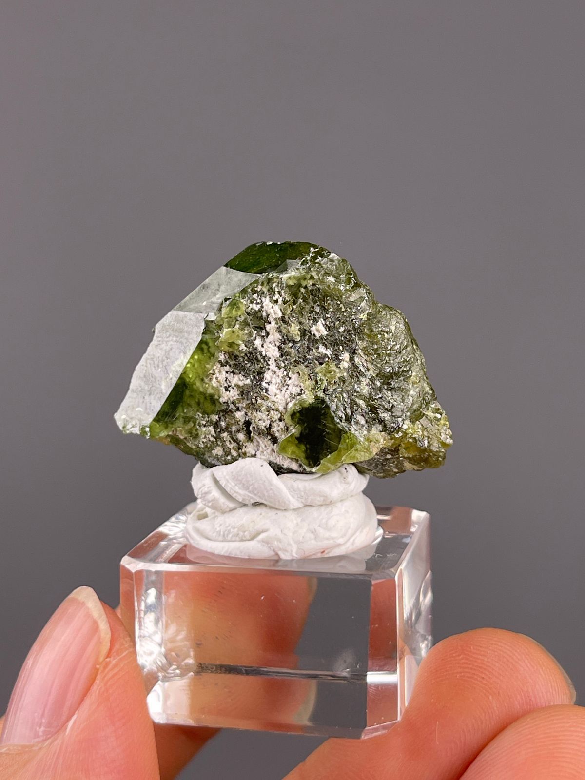 Tourmaline from Brazil: compact green crystal with pale granular material across its face.