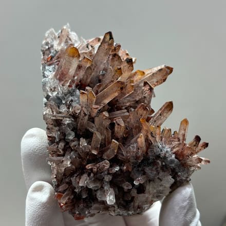 Red-skinned quartz cluster from Guangdong, China, held in gloved hand