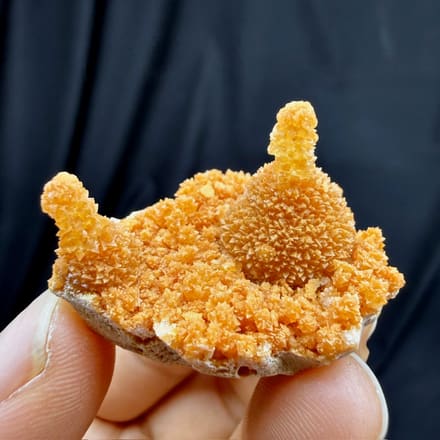 Orange stalactitic calcite crown with sugary skin from Yunnan, China, held in hand