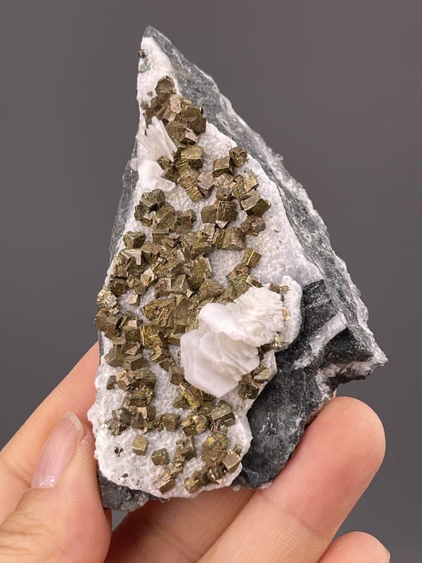 Close-up of pyrite crystals showing metallic luster on calcite