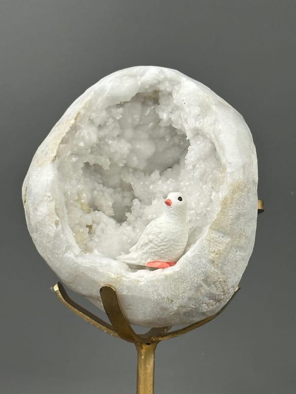 Side view of large quartz geode on gold stand