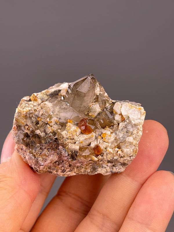 SiO₂ trigonal smoky quartz with isometric garnet and dolomite rhombs