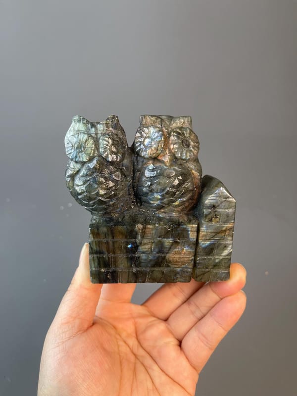 Hand-carved labradorite owl sculpture showing vivid labradorescence