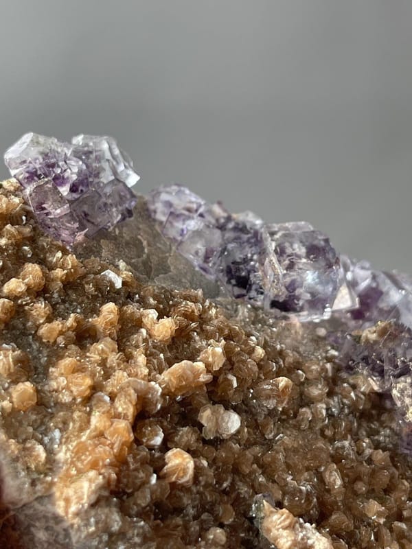 Purple phantom fluorite with mica base displaying vitreous luster