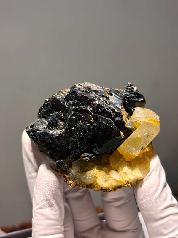 Black cassiterite plate with yellow aquamarine from Xuebaoding, Sichuan, China, close-up of the crystal faces