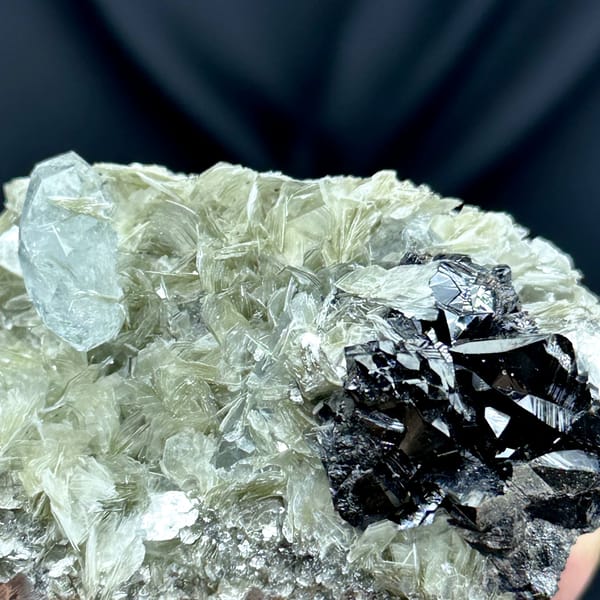 Black cassiterite and pale aquamarine prism on muscovite from Xuebaoding, Sichuan, China, reverse side
