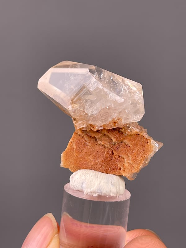 Clear prismatic crystal on brown matrix visible on calcite specimen from Daye, Hubei, China