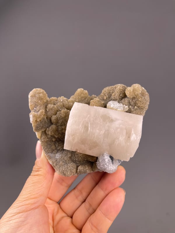 Calcite from Fujian, China: broad pale crystal above brown matrix.