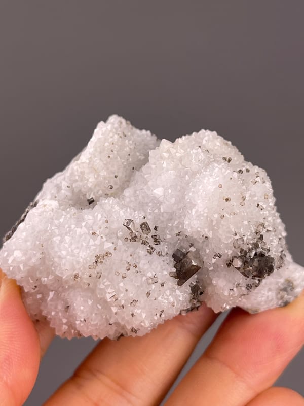 Calcite from Fujian, China: white granular surface with scattered brown crystals.
