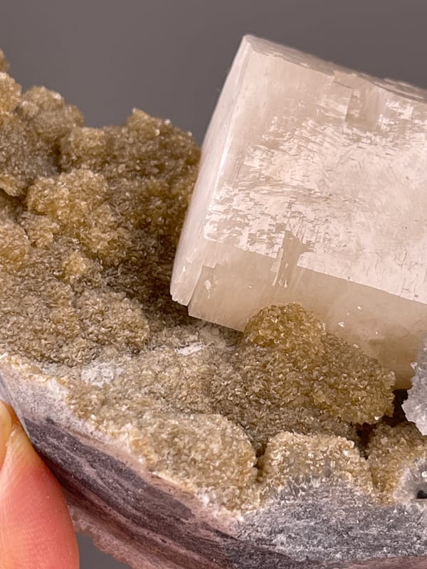 Calcite from Fujian, China: crystal edge meeting granular brown matrix.