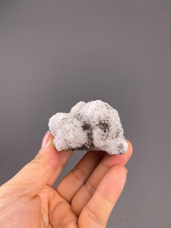 Calcite from Fujian, China: whole white-and-brown specimen above the palm.