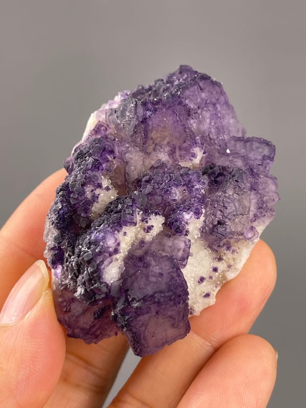 Calcite from Guizhou, China: upright angle exposing broad lavender faces and white grains.