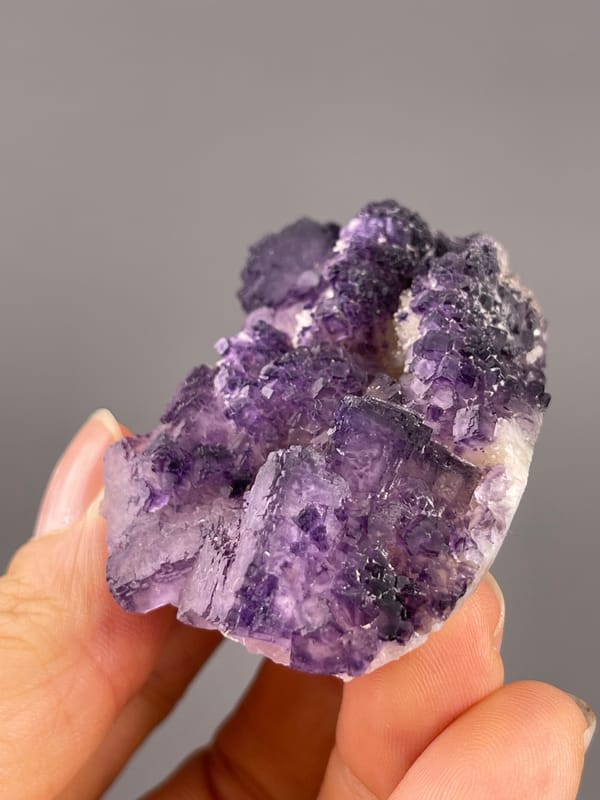Calcite from Guizhou, China: side view of stepped purple edges above pale matrix.