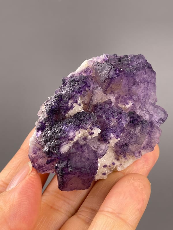 Calcite from Guizhou, China: tilted close view of white granular patches among purple faces.