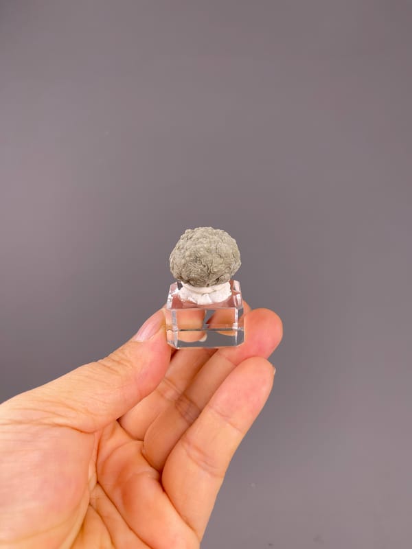 Calcite from Huanggangliang, Inner Mongolia, China: whole small rounded specimen above the palm.