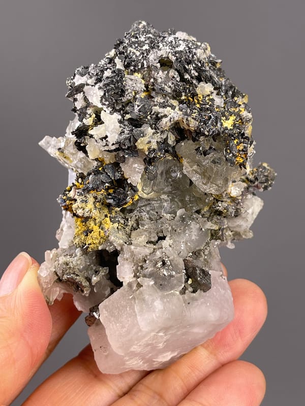 Calcite from Inner Mongolia, China: elongated upright view with scattered yellow surface patches.
