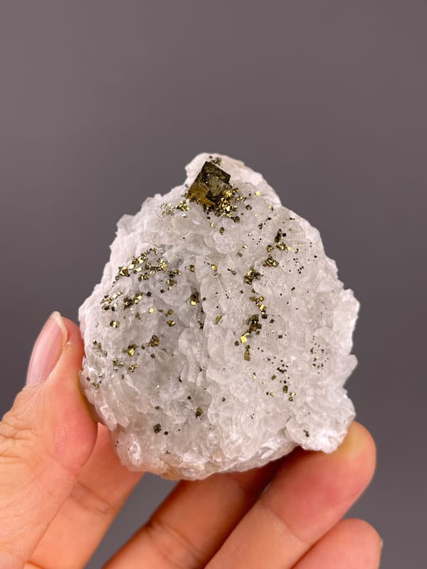 Calcite from Longyan, Fujian, China: white crystalline face with a larger brassy crystal near the tip.