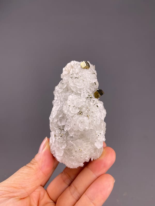 Calcite from Longyan, Fujian, China: whole white layered mass with scattered brassy crystals.