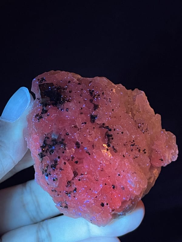Calcite from Longyan, Fujian, China: angled fluorescence view showing pink growths and dark grains.