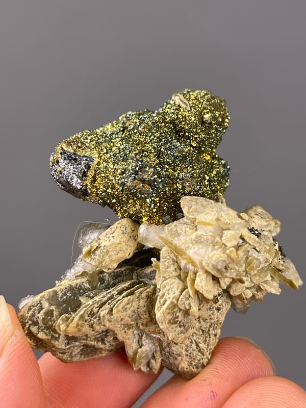 Brassy masses above tan blades on natural calcite specimen from China