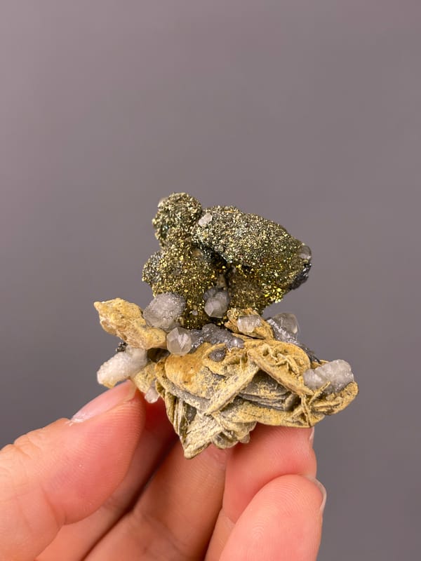 Calcite specimen from China bearing brassy masses above tan blades