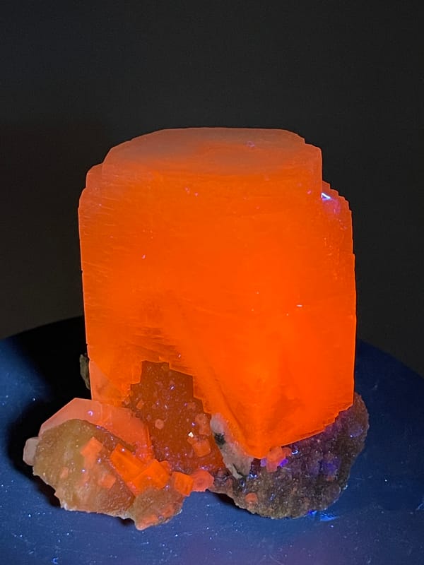 Calcite specimen from Fujian, China showcasing bright orange-red fluorescence under ultraviolet light