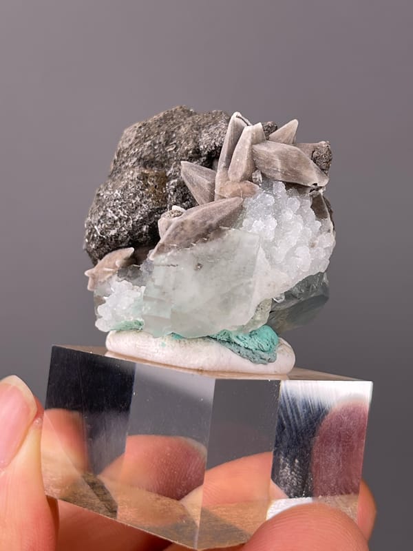 Dark globules with tan blades and green crystal visible on calcite specimen from Longyan, Fujian, China