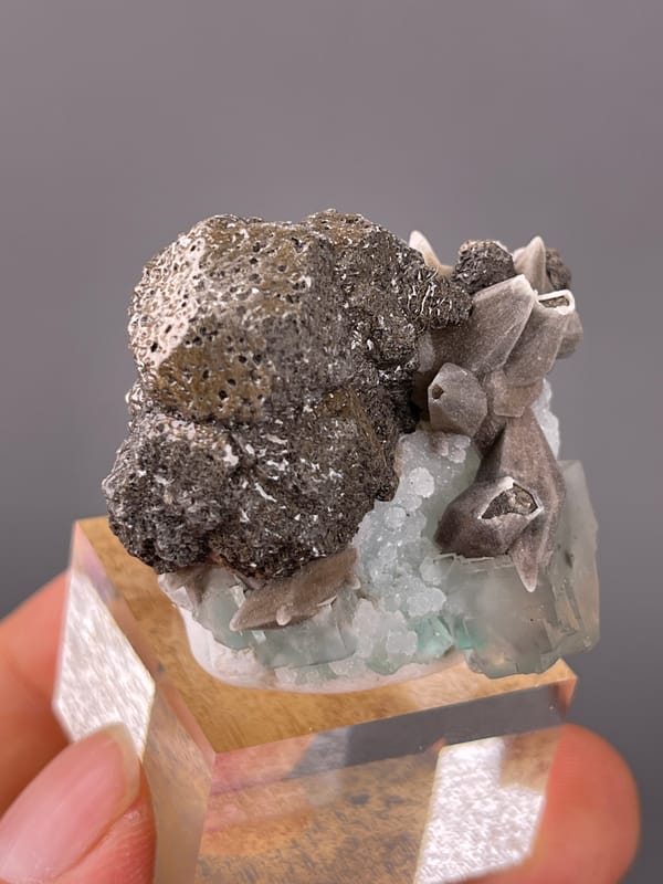 Dark globules with tan blades and green crystal on natural calcite specimen from Longyan, Fujian, China